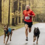 homem correndo com cachorros correndo ao seu lado maratona corrida